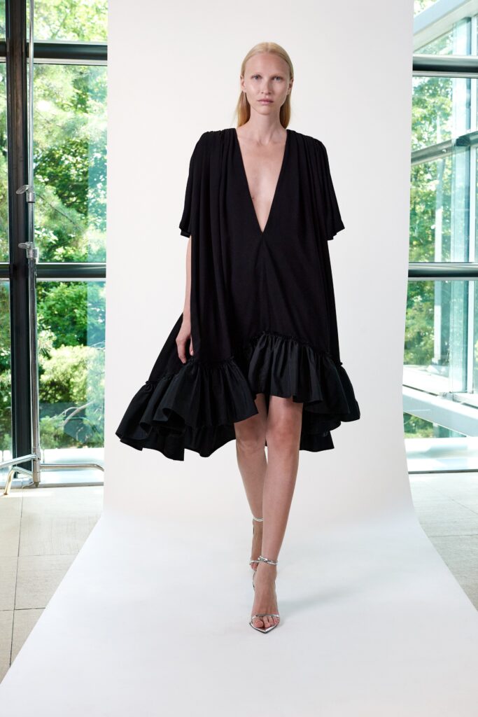 A relaxed black dress with short sleeves, a V-neckline, and a tiered silhouette.