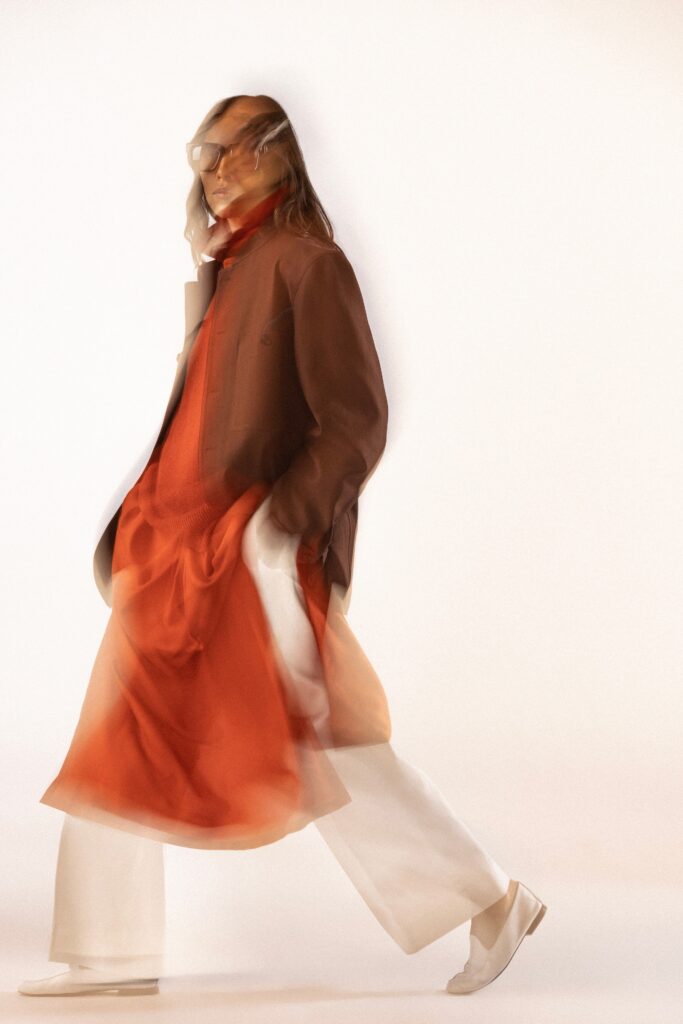A relaxed brown layered dress paired with a long-sleeve collared jacket.