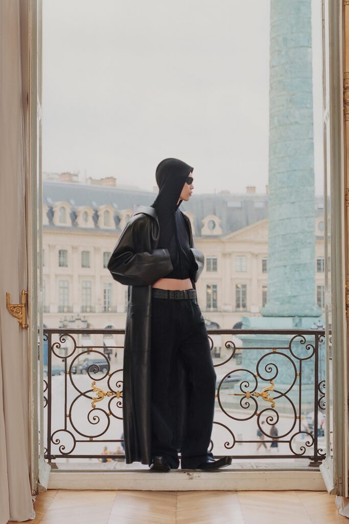 A fitted black leather coat with a hood and asymmetric design paired with matching pants.