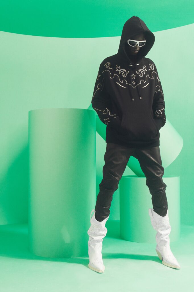 An oversized black hoodie paired with sleek leather pants and stylish white boots.