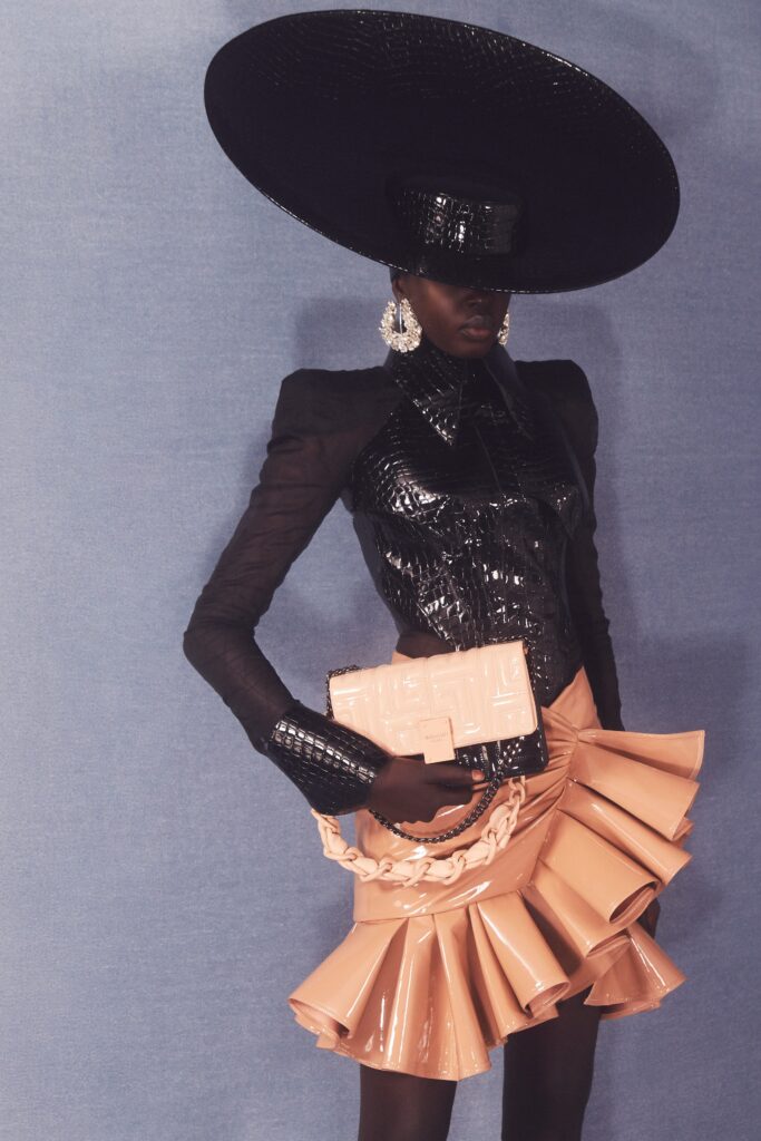 A fitted black leather blazer with long sleeves and a pleated asymmetric pink skirt.