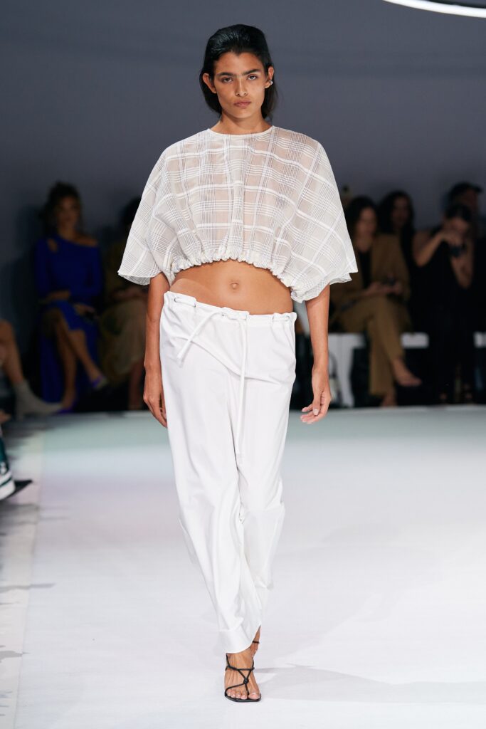A relaxed white cropped top with short sleeves paired with pleated pants.