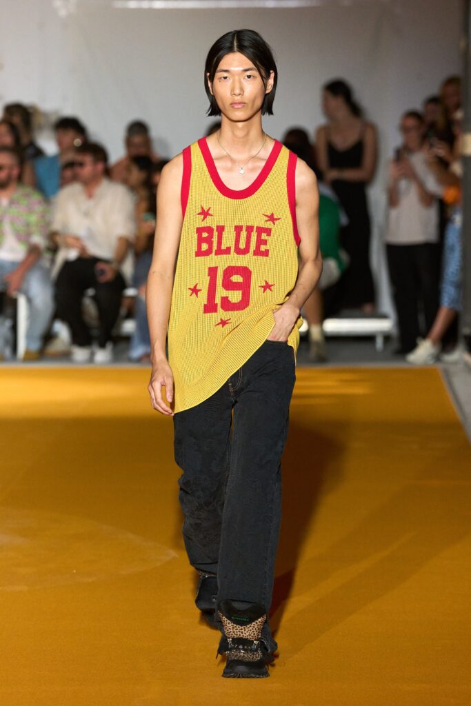 A relaxed yellow printed tank-top paired with black pants for a casual runway look.