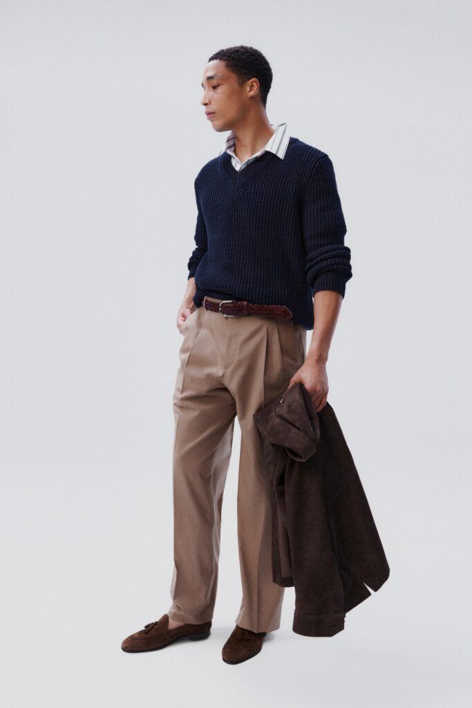 A relaxed navy sweater paired with pleated beige pants, featuring a collared shirt underneath.