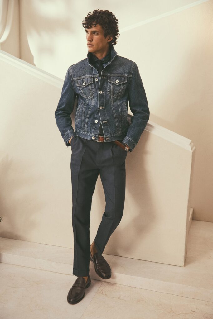 A fitted blue denim jacket with long sleeves paired with black straight-leg pants.