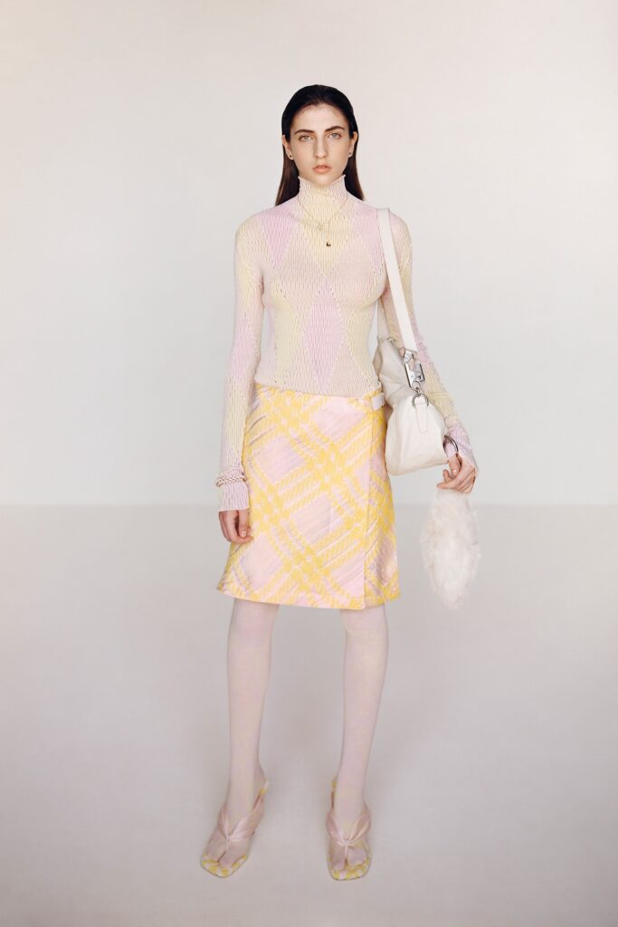 A fitted pink mesh long-sleeve top paired with a checked yellow skirt.