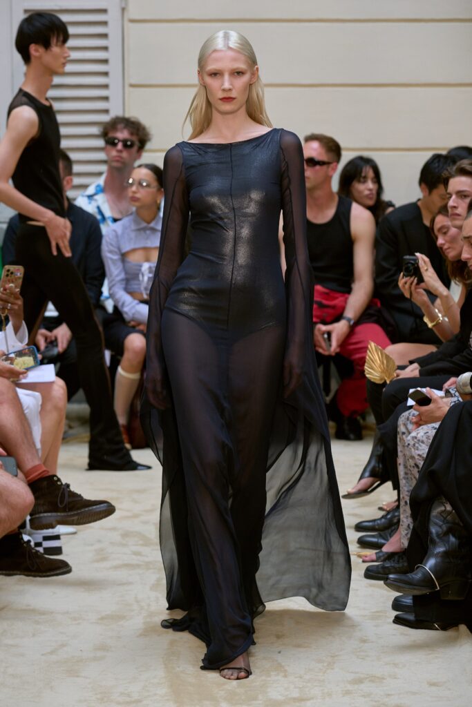 A fitted black silk dress with long sleeves, a V-neckline, and sheer detailing.