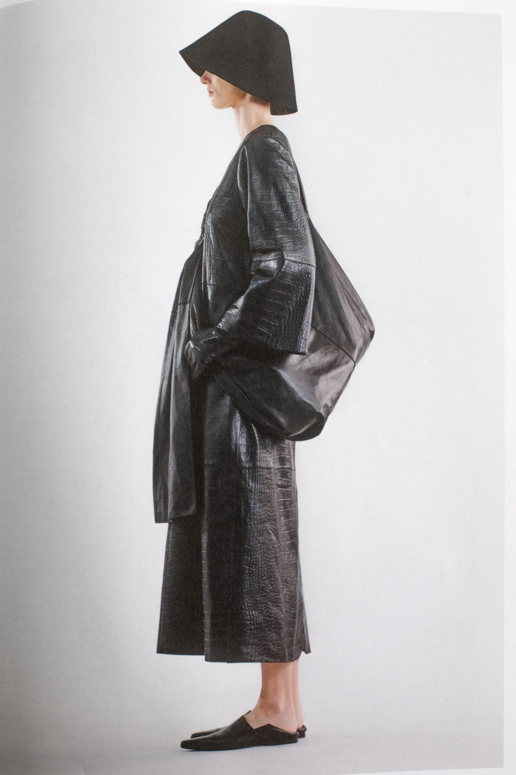 A relaxed black leather dress with long sleeves and a V-neckline featuring a layered design.