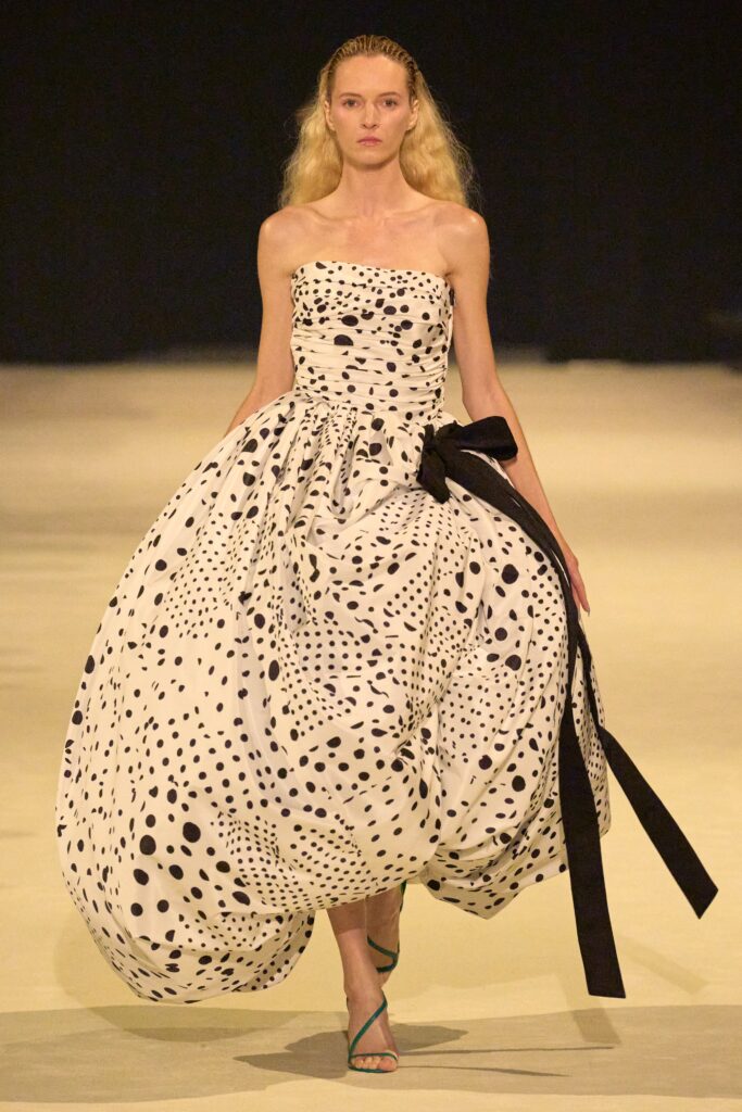 A relaxed strapless dress featuring a tiered silhouette with black polka dots on a white background.