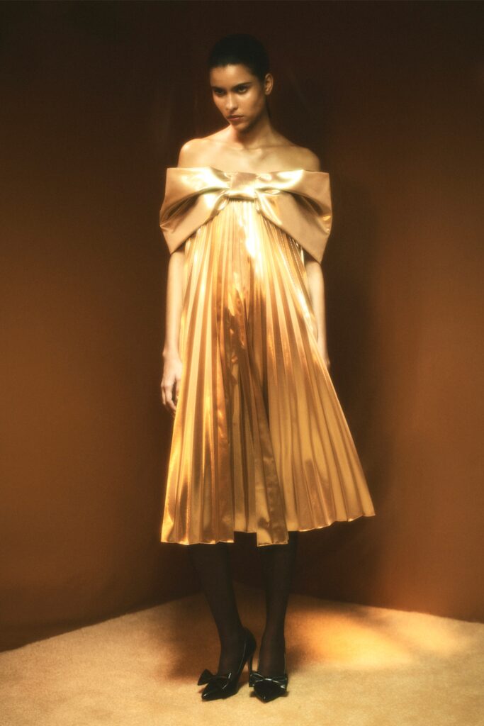 A relaxed gold silk off-shoulder dress with a pleated design.