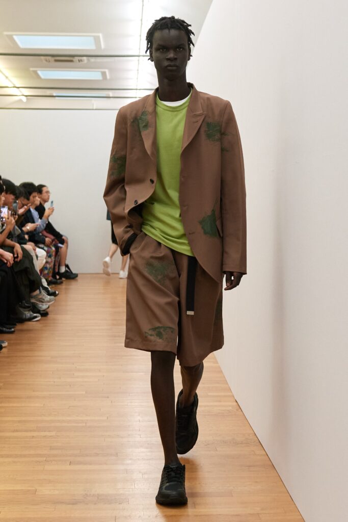 A relaxed brown jacket paired with a green short-sleeve shirt and matching shorts.