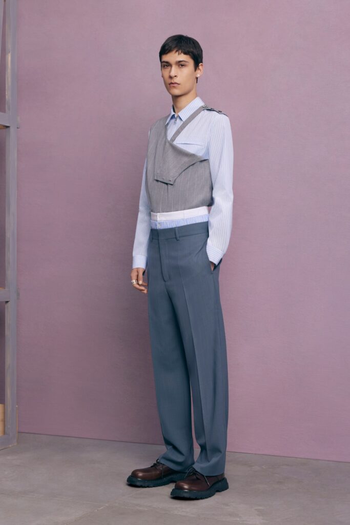 A fitted gray vest over a long-sleeve shirt paired with blue trousers for a modern look.