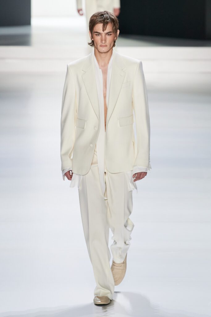 A tailored white suit with long sleeves and a collared design, featuring buttoned details.