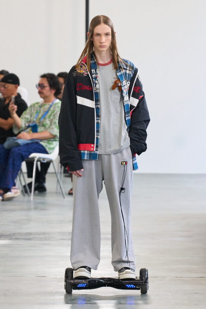 A relaxed black jacket with a printed design paired with gray pants.