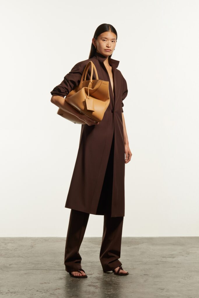 A fitted brown coat with long sleeves and a collared neckline paired with straight-leg pants.