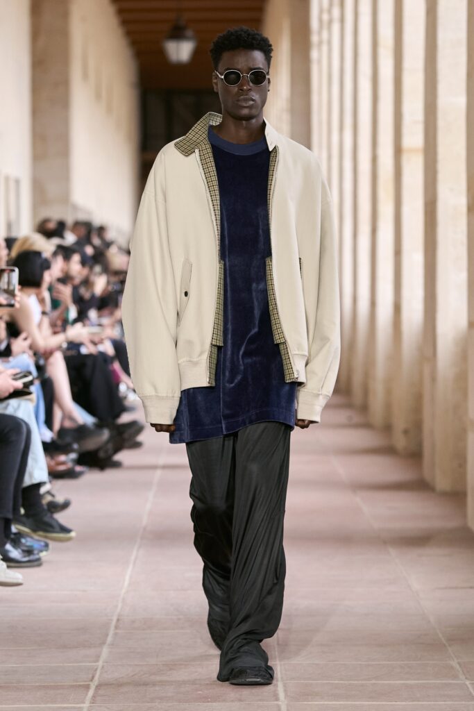 A relaxed beige jacket layered over a blue velvet dress with long sleeves.