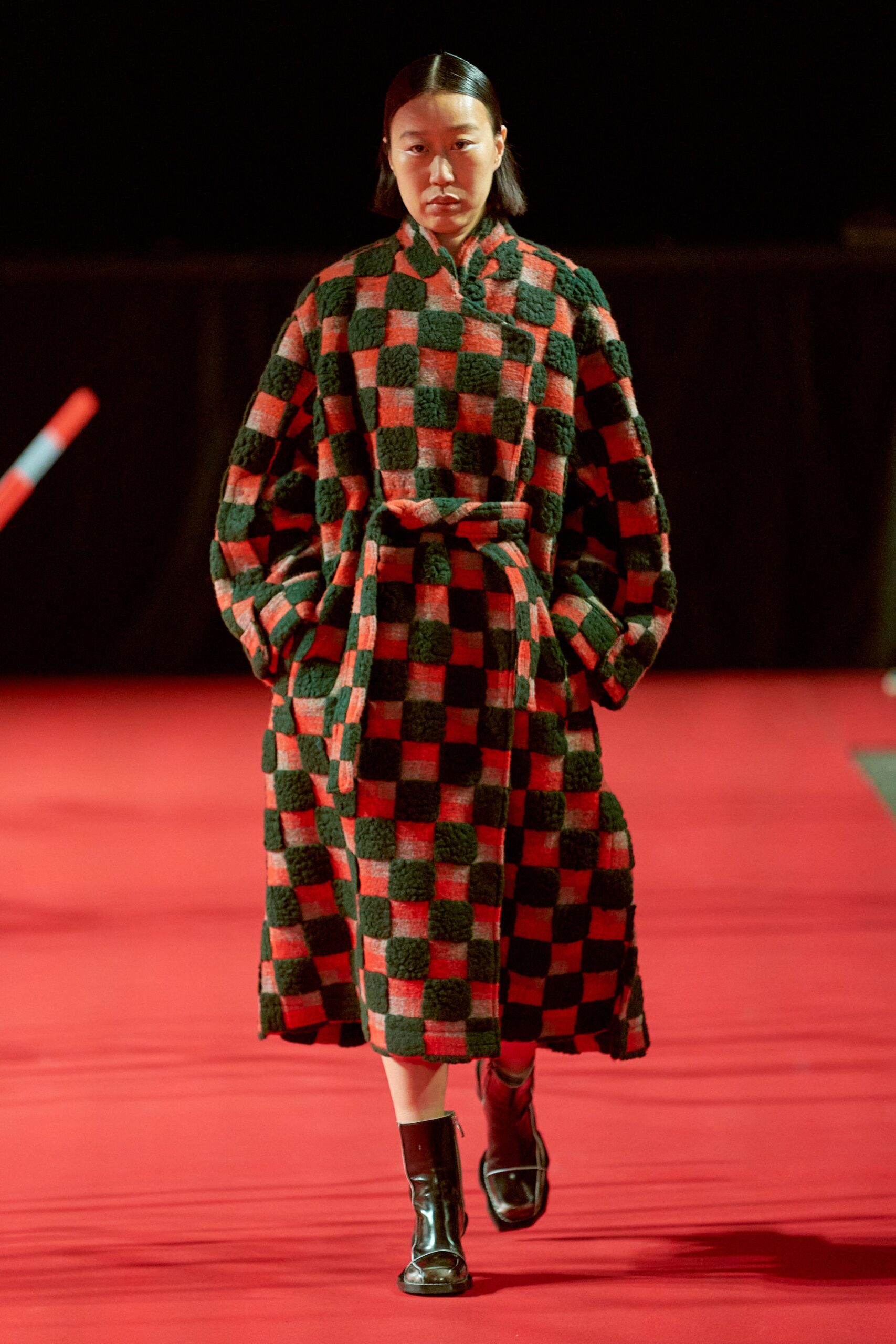 A relaxed black and red checked coat with long sleeves and a collared design.