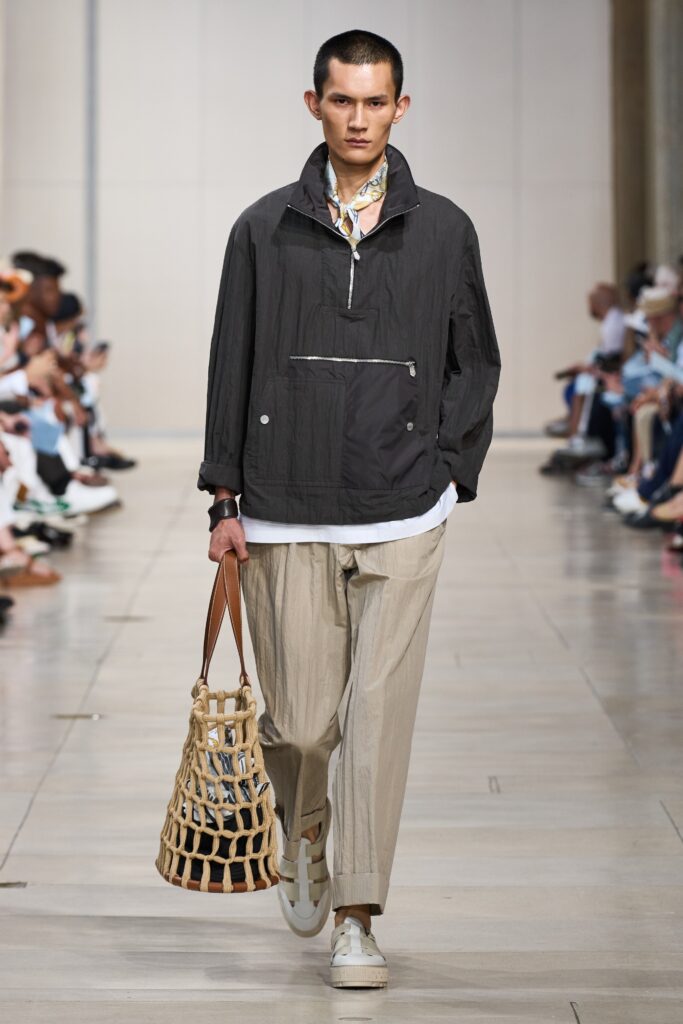 A relaxed black cotton jacket with a collared neckline paired with straight-leg beige pants.