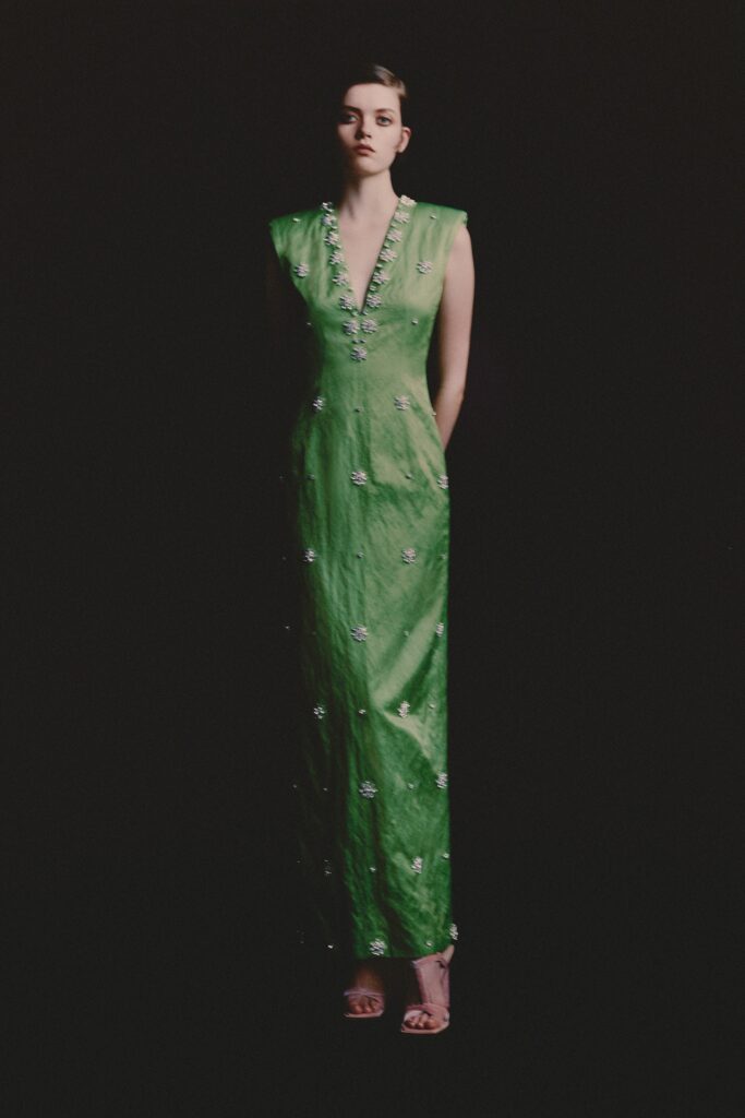 A fitted green silk dress with a V-neckline and embroidered detailing.