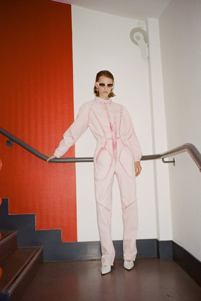A fitted pink denim jumpsuit with long sleeves and a zippered front.