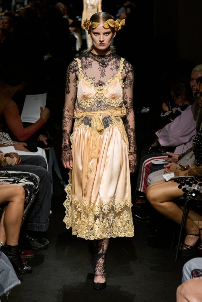 A fitted cream dress with lace detailing, featuring a sleeveless design and v-neckline.