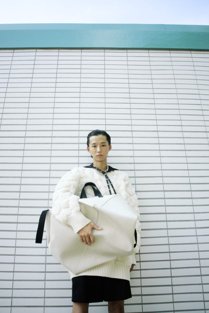 A relaxed white long-sleeve sweater with a collared design paired with a high-waisted black skirt.