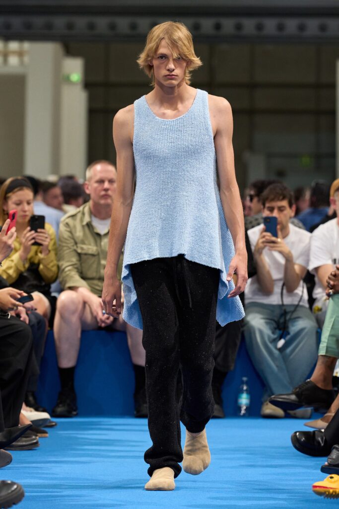 A relaxed blue cotton sleeveless top paired with black relaxed pants featuring an asymmetric design.