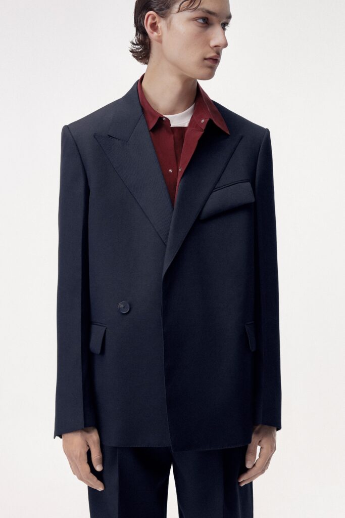 An oversized navy blazer paired with a collared red shirt, featuring buttoned details.