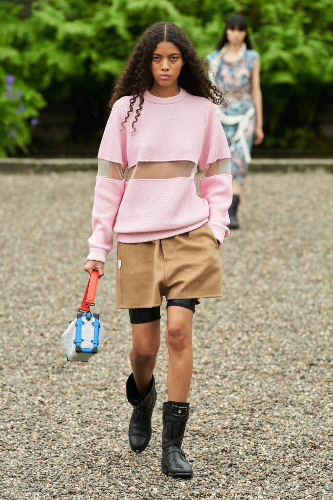A relaxed pink sweater paired with brown shorts, featuring a layered design.