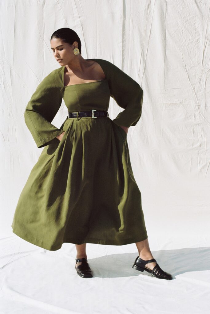 A relaxed green cotton dress with long sleeves and a tiered design.