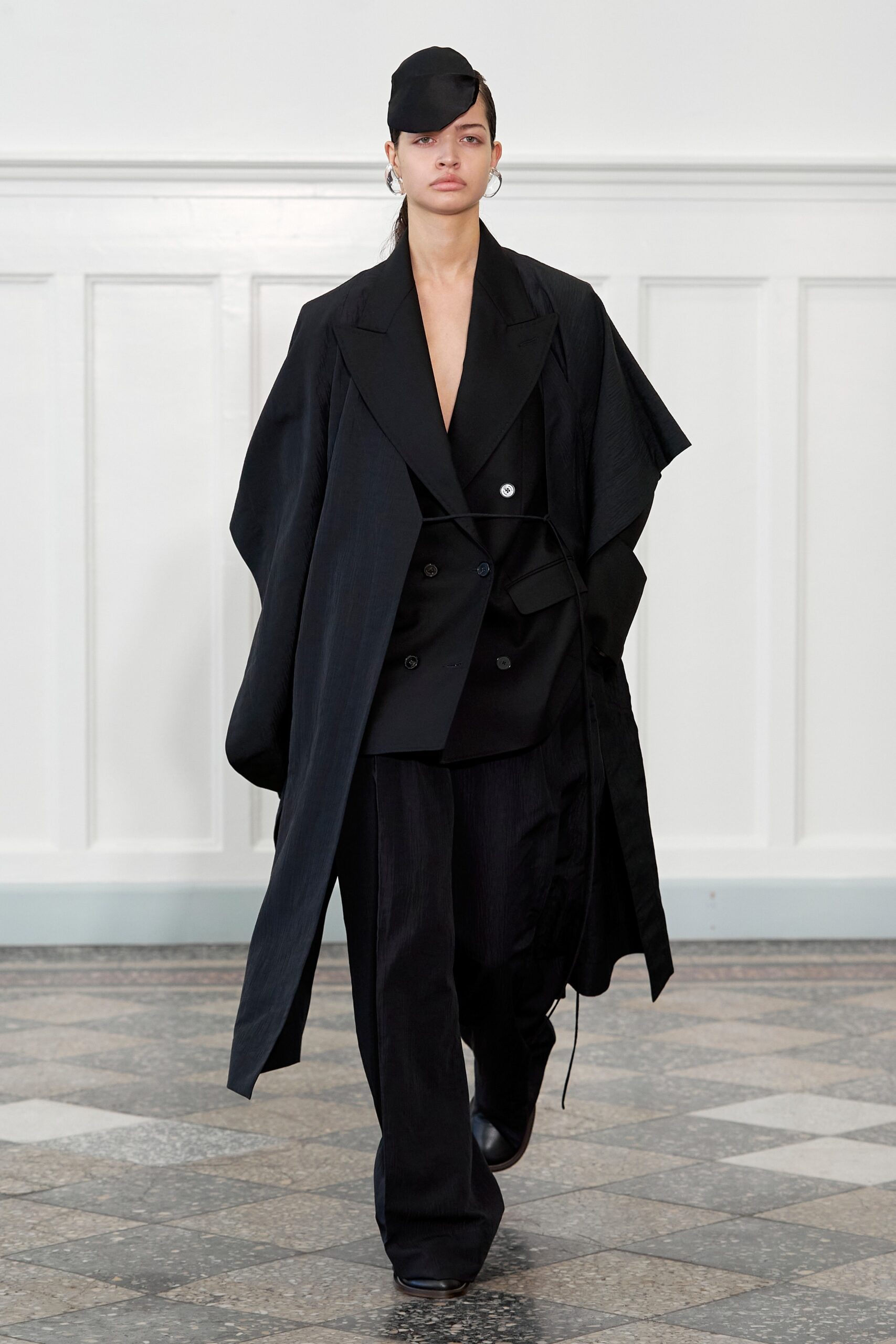 A relaxed black wool coat with an asymmetric design paired with matching pants.