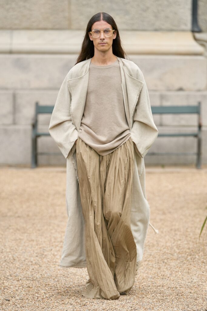 A relaxed beige coat paired with a matching top featuring pleated details.