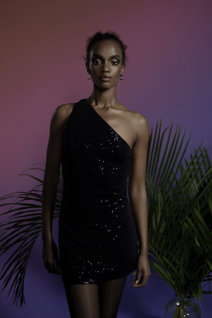 A fitted black sequin mini dress with an asymmetric design and sleeveless construction.