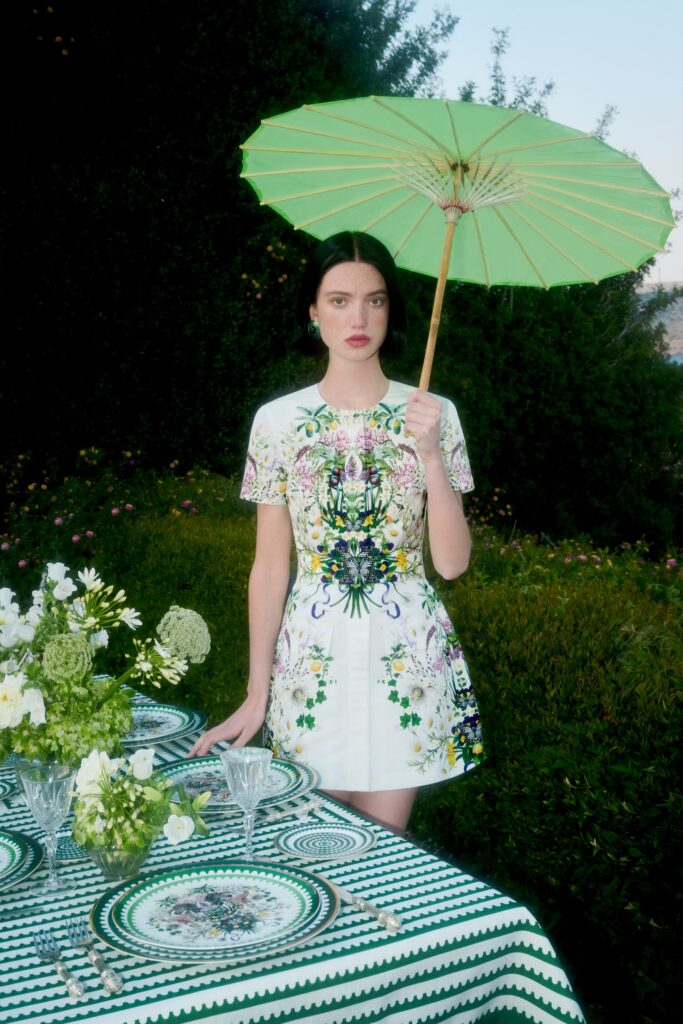 A fitted white dress with short sleeves, a collared neckline, and floral design details.