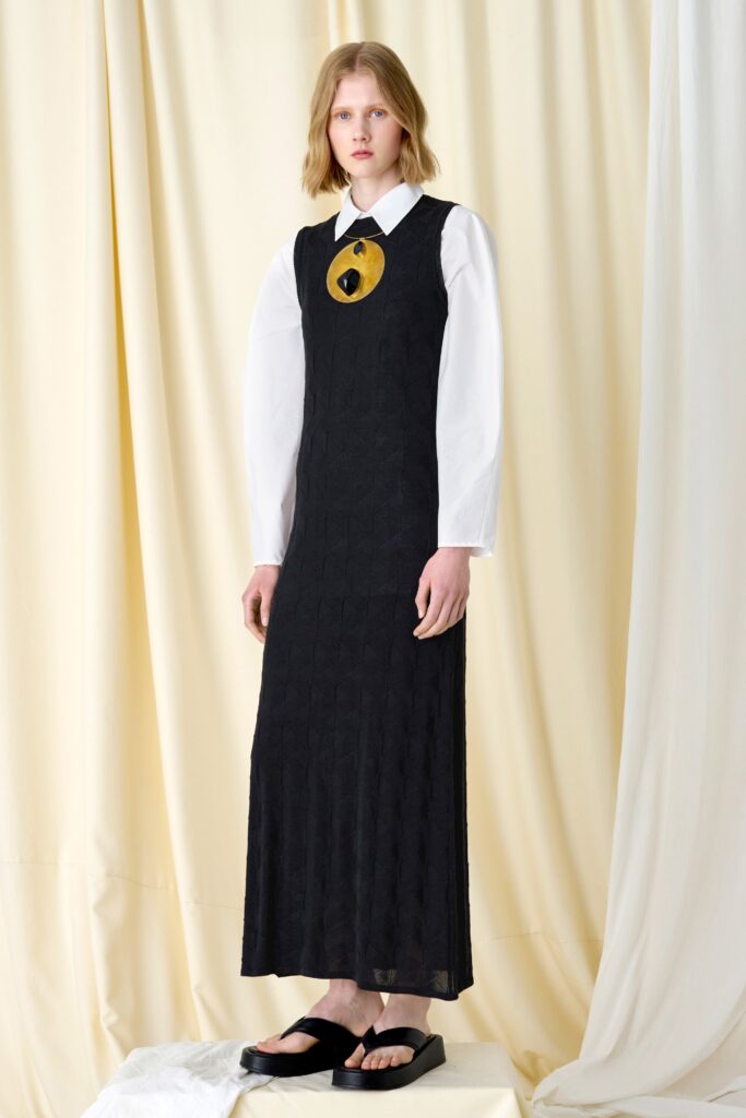 A fitted black cotton dress with long sleeves and a collared neckline.