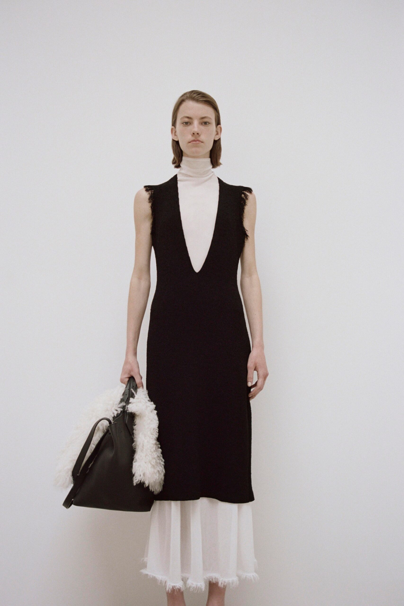 A fitted black dress layered over a white base with a V-neckline and sleeveless design.