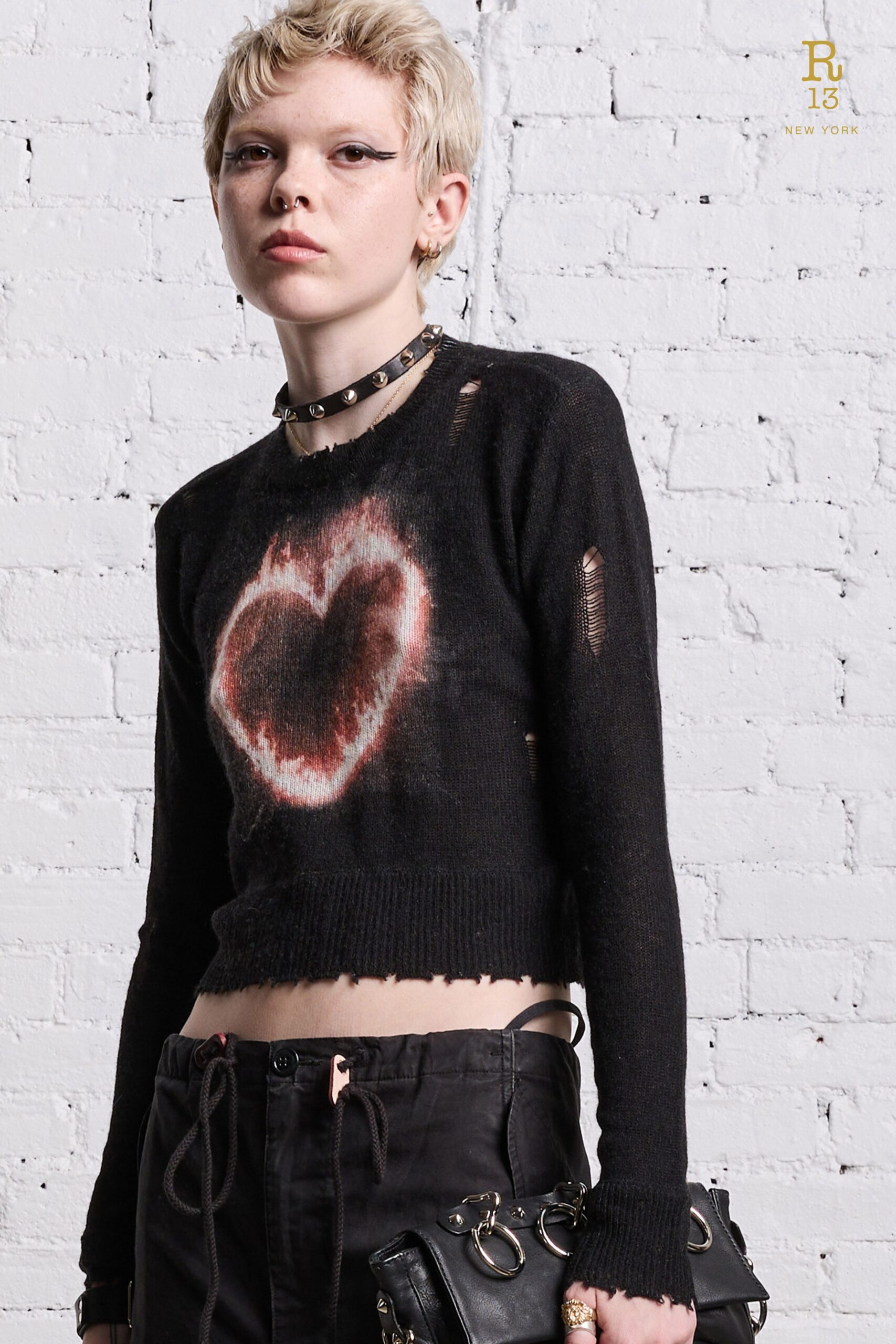 A cropped black sweater with a heart print paired with black pants, featuring a distressed look.