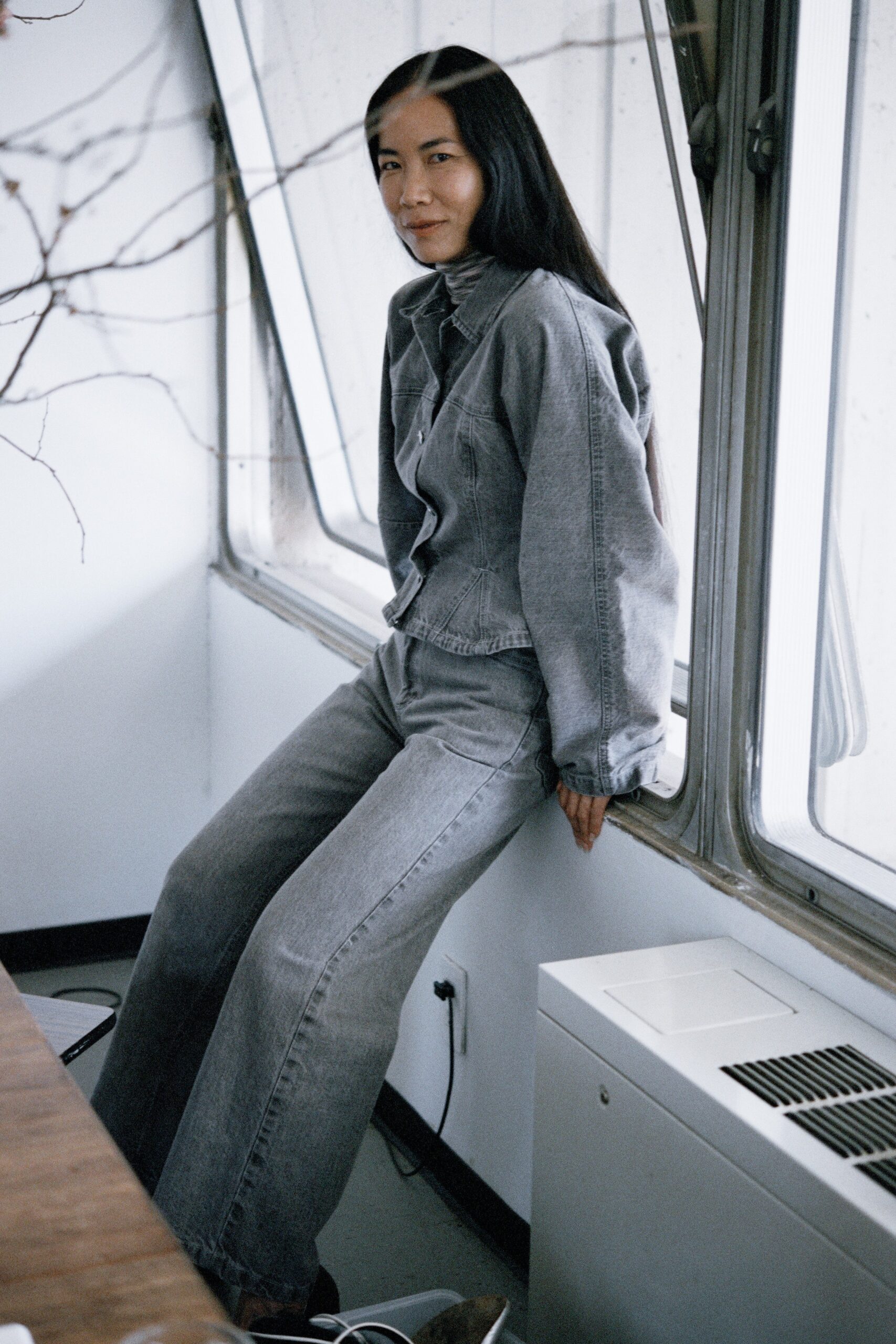 A relaxed gray denim jacket with long sleeves and a collared design, paired with wide-leg pants.