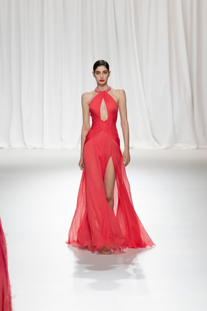 A fitted red chiffon dress with a halter neckline and an asymmetric slit design.