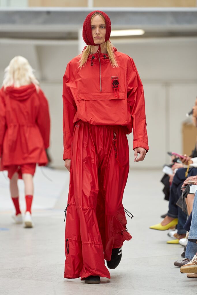 A relaxed red jacket with a hood and matching pants featuring zippered details.