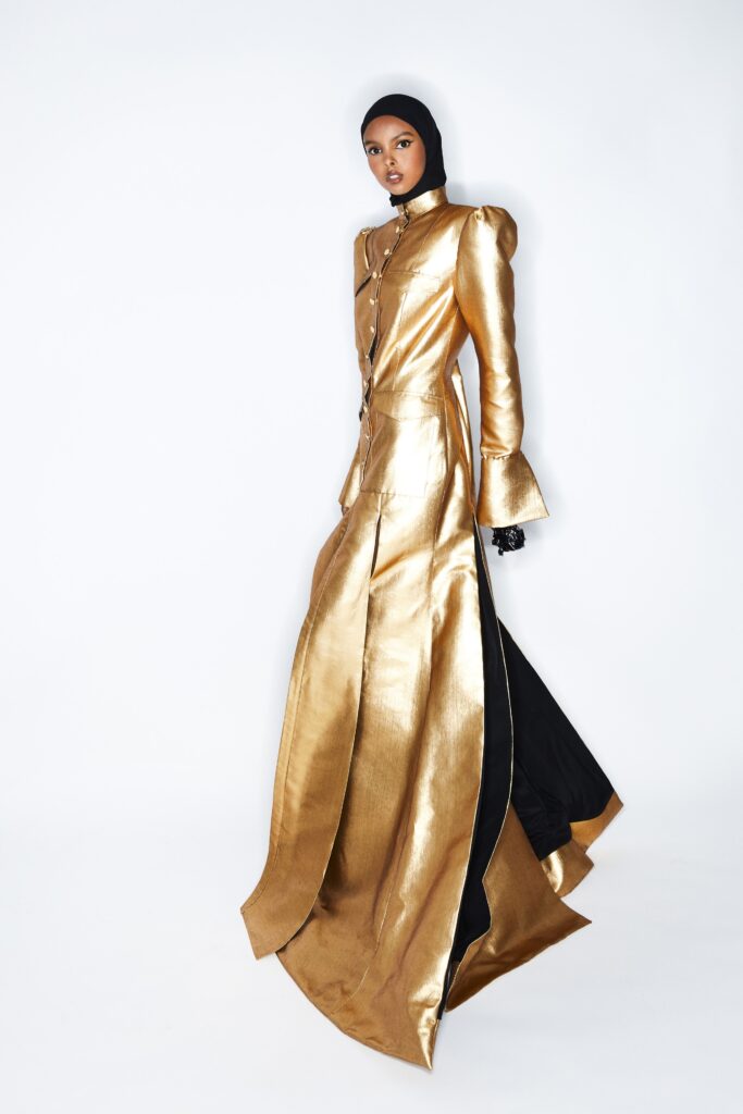 A fitted gold silk dress with long sleeves, a collared neckline, and an asymmetric design.