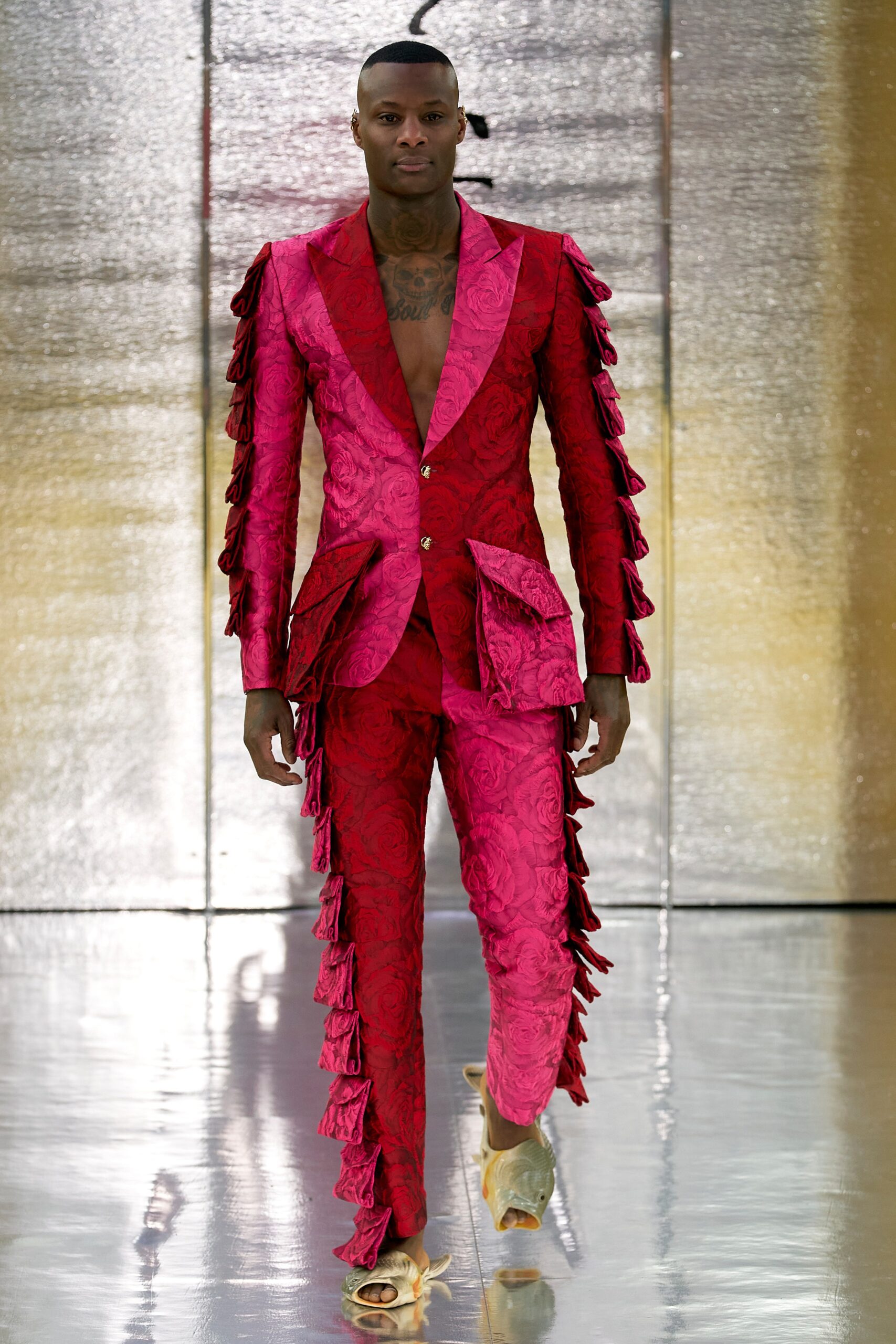 A fitted red silk suit with a V-neckline and fringed detailing.