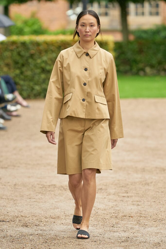A relaxed beige cotton jacket with long sleeves and collared design paired with matching shorts.