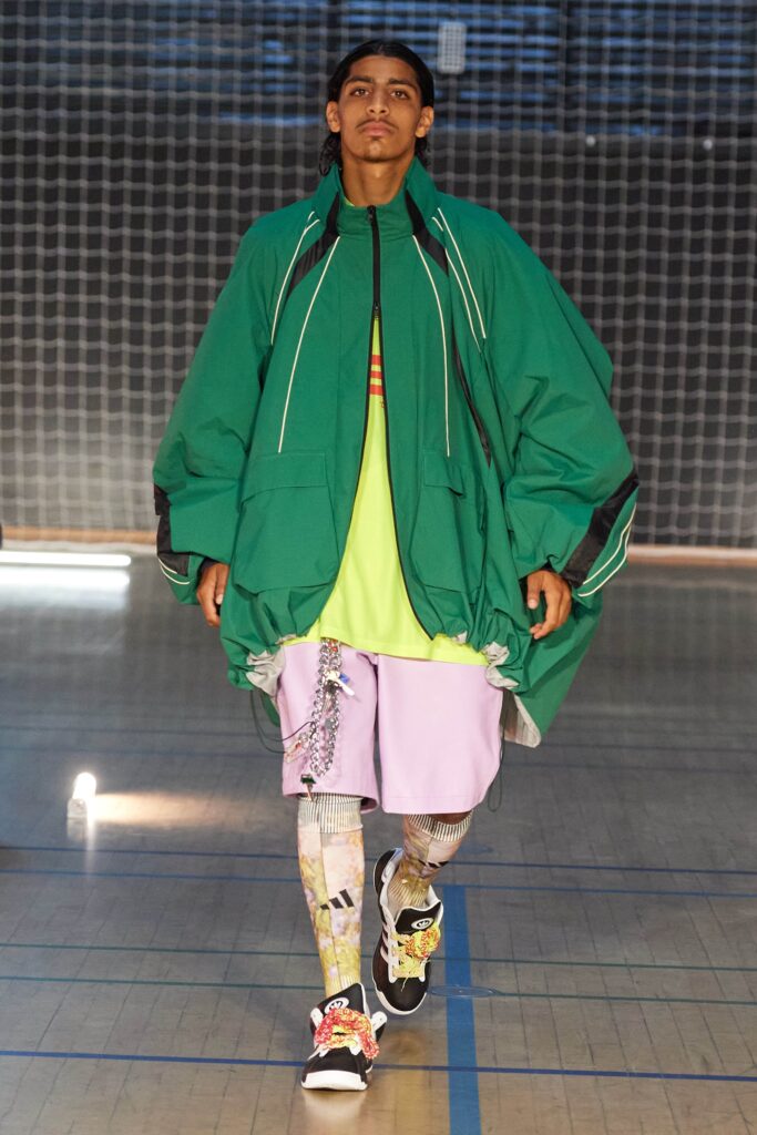 An oversized green jacket paired with purple shorts, showcasing a layered streetwear style.
