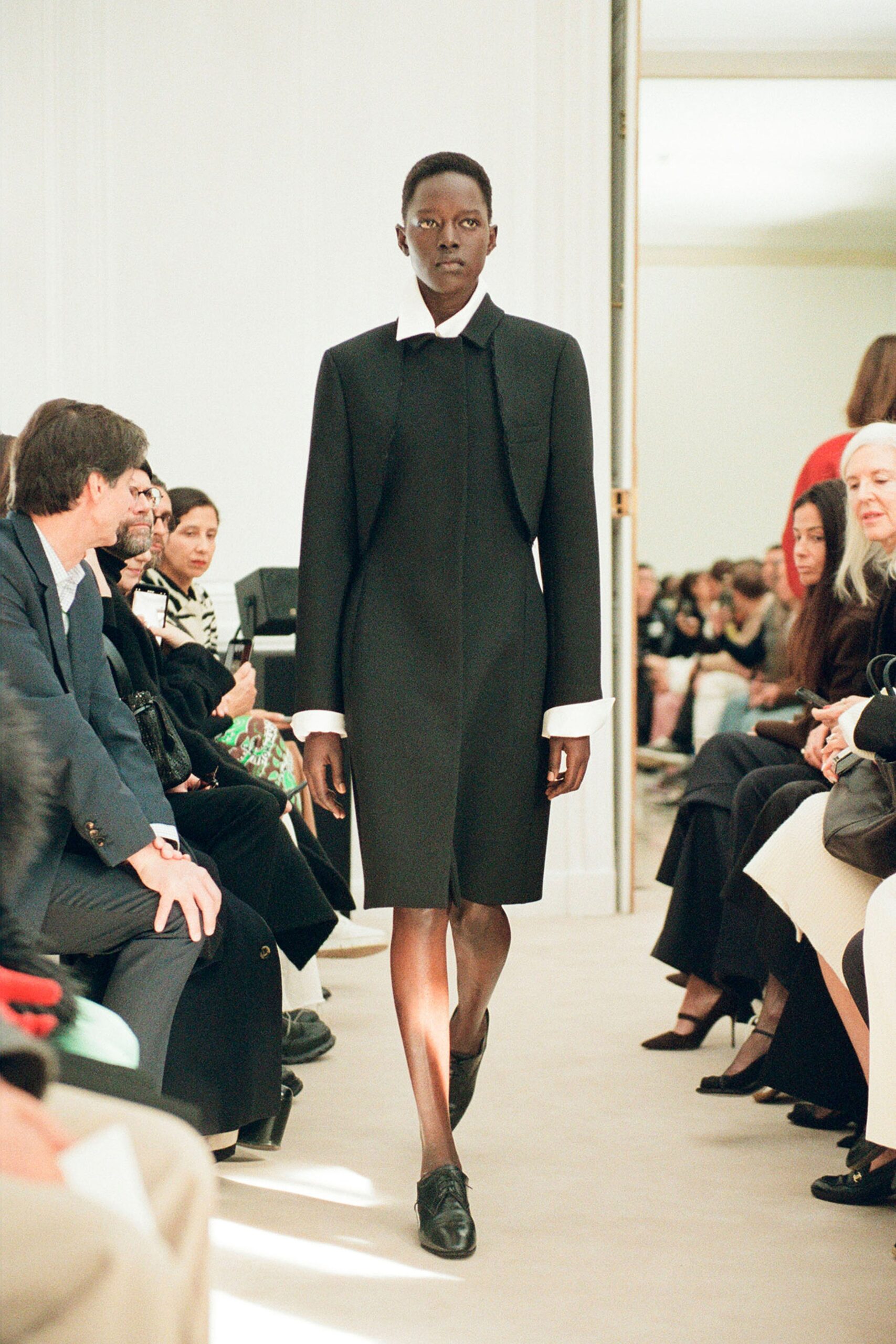 A fitted black cotton dress with long sleeves and a collared neckline.