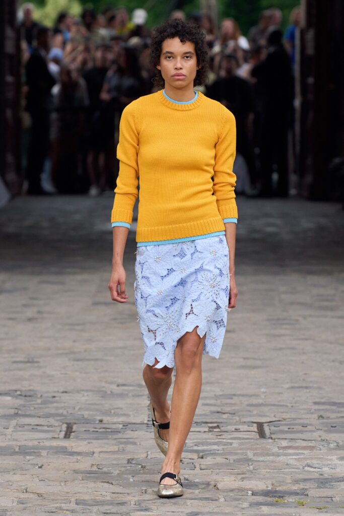A fitted yellow cotton long-sleeve sweater paired with an asymmetric blue skirt.