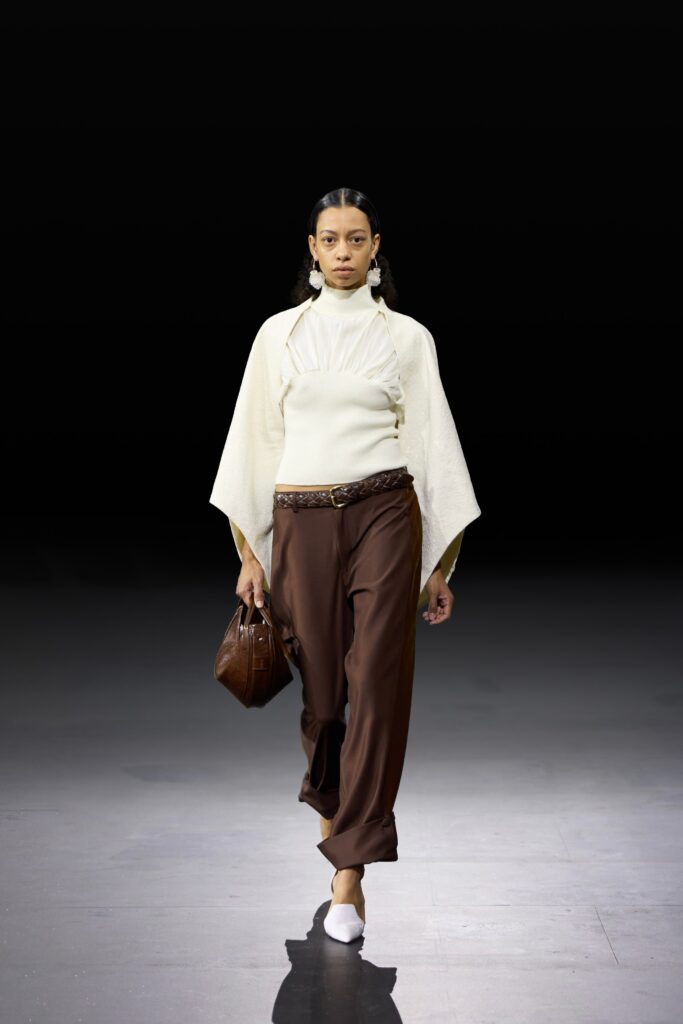 A white pleated long-sleeve top paired with brown silk pants for a chic look.