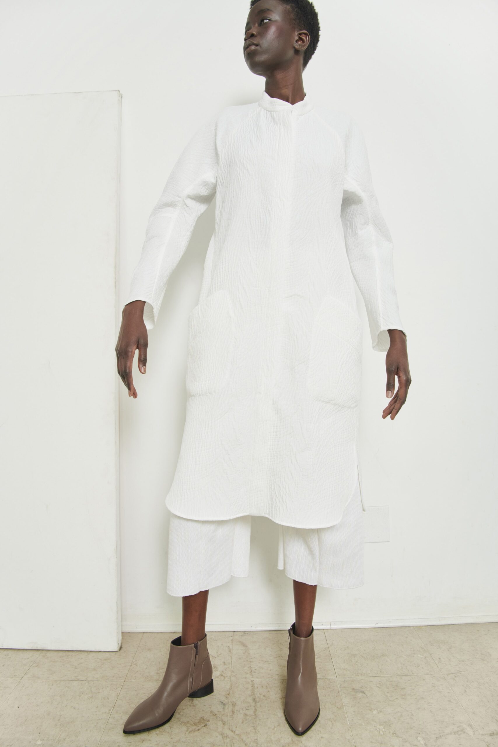 A relaxed white coat with long sleeves and a collared neckline, featuring straight-leg trousers.