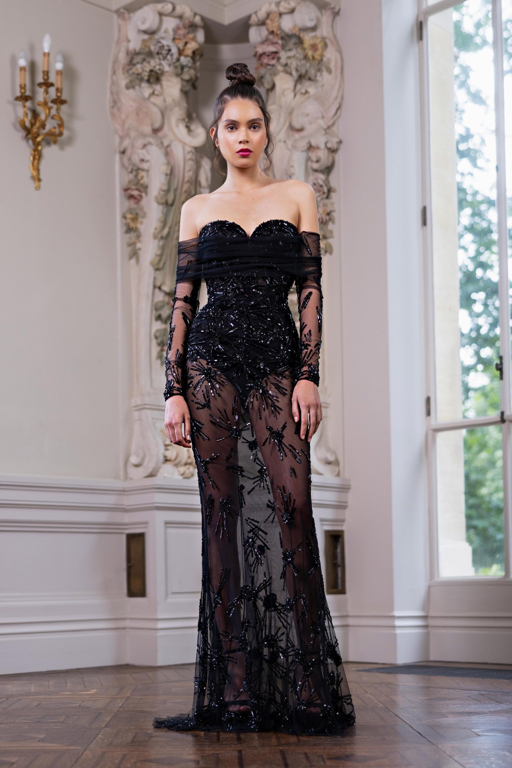 A fitted black lace off-shoulder gown with sheer and embroidered details.