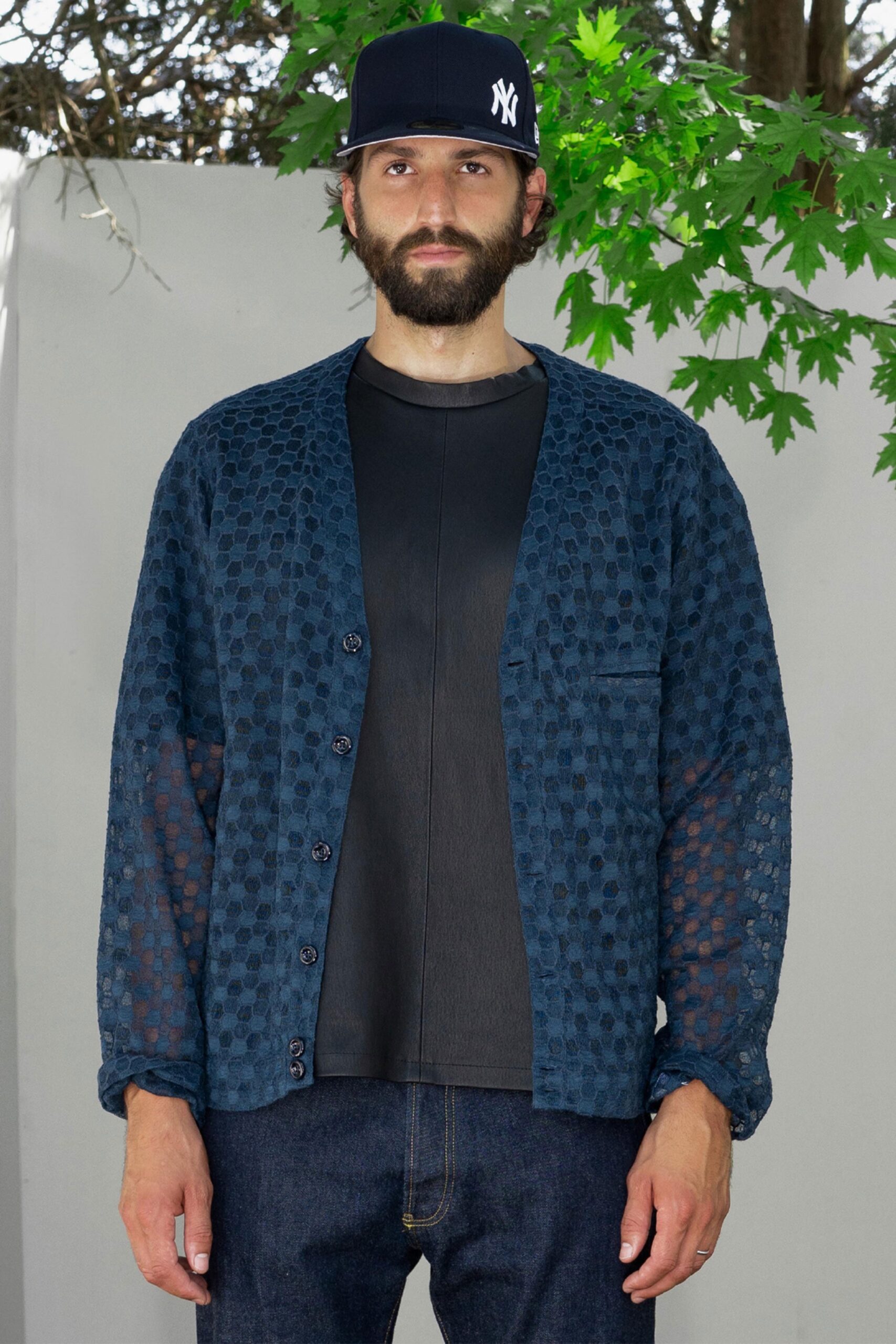 A relaxed blue cotton jacket with long sleeves and a buttoned front, layered over a black top.